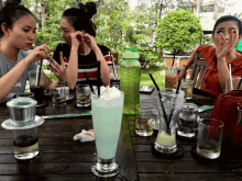 a group of women are sitting at a table with drinks and a bottle that says " i love " on it