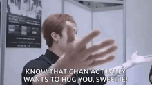 a man in a black shirt is hugging another man in a room .