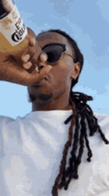 a man is drinking a bottle of corona beer .