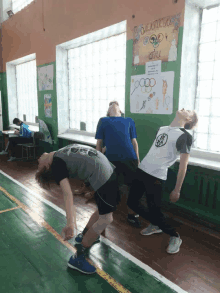 a group of boys are doing exercises in front of a wall that says olympics on it