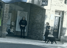 a woman walking a dog in front of a store called m&co