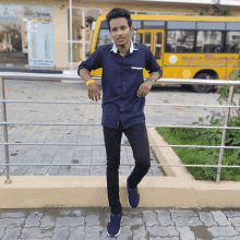 a young man stands in front of a yellow school bus that says ' shree ram ' on the side