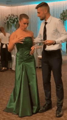 a woman in a green dress is standing next to a man