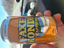 a person is holding a can of faxe kondi appelsin