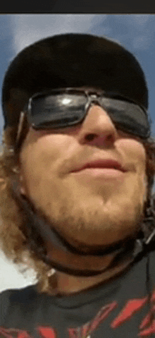 a man wearing sunglasses and a helmet is smiling