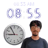 a man stands in front of a wall clock that says 8:55 am