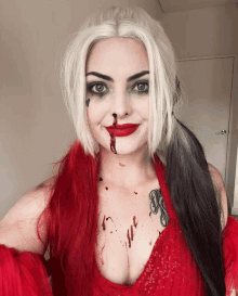 a woman in a harley quinn costume has blood on her face and chest