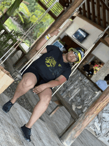 a woman is sitting on a swing wearing a jamaica hat