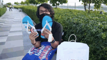 a man wearing a mask holds up a pair of flip flops next to a bag that says captain america