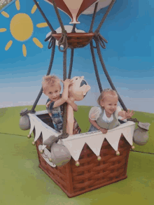 two children are riding in a hot air balloon which says ' snoopy ' on it