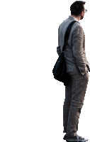 a man in a suit is standing with his hands in his pockets and carrying a black bag