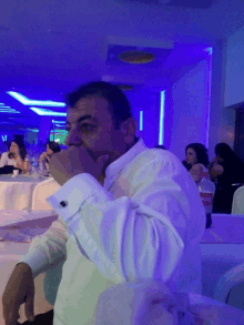 a man in a white shirt sits at a table with a coca cola bottle