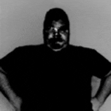 a man in a black shirt is standing with his hands on his hips in a blurry photo .