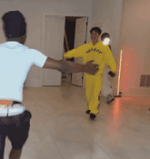 a man in a yellow ap5der hoodie is dancing with another man in a white shirt