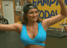 a woman in a blue tank top is smiling in front of a sign that says ' champions today '