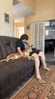 a boy sits on a couch with his dog