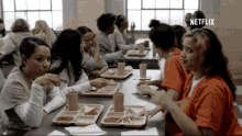 a group of women are sitting at a table with trays of food and a netflix logo in the corner