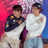 a man wearing a red bull hoodie sits next to another man wearing a white shirt