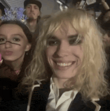 a woman with blonde hair is smiling in a crowd of people