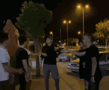 a group of men are standing next to each other on a sidewalk at night .