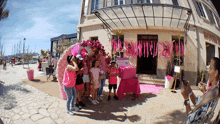 a woman takes a picture of a group of people in front of a building that says " boutique " on it