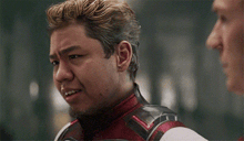 a man in a superhero costume is making a funny face while standing next to another man .
