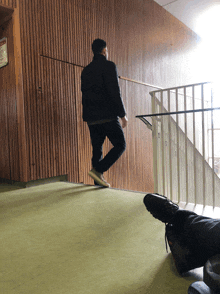 a man walking down a set of stairs with a sign on the wall that says ' emergency exit '