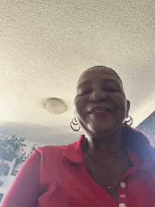 a woman in a red shirt and earrings smiles for the camera