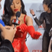 a woman in a red dress and red gloves is dancing on a red carpet .