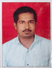 a man in a blue shirt stands in front of a red backdrop