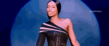 a woman in a black corset is making a funny face while standing in front of a blue background .