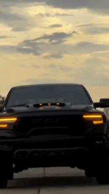 a black ram truck is parked on the side of a road at sunset .