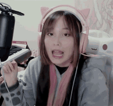 a girl wearing pink headphones with cat ears is sitting in front of a microphone