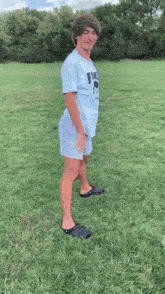 a young man wearing a blue shirt with the word fire on it is standing in the grass