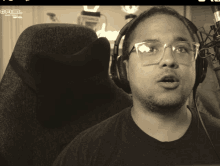 a man wearing glasses and headphones stands in front of a microphone with gfuel written on the bottom of the screen