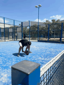 a man is kneeling down on a blue tennis court holding a paddle