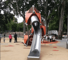 people playing in a playground with a slide that looks like a rocket