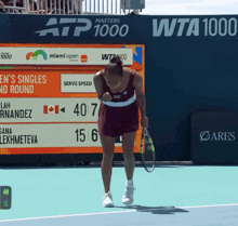 a woman holding a tennis racquet stands in front of a scoreboard that says atp 1000