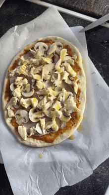 a pizza with mushrooms and cheese on it is sitting on a piece of wax paper