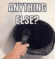 a person is holding a microphone in front of a trash can with the words `` anything else ? '' written on it .