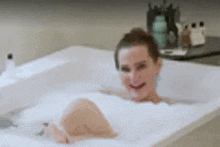 a woman is taking a bath in a bathtub full of foam .