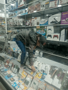 a man in a black hat is looking through a glass display case filled with lots of electronics