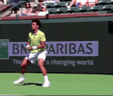 a man playing tennis in front of a bn paribas ad