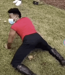 a man wearing a red shirt and black pants is kneeling on the grass .