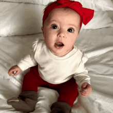 a baby wearing a red headband and red pants