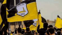 a crowd of people are holding up yellow and black flags with the letters eaei on them .