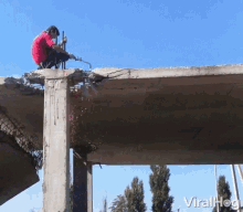 a man in a red shirt is kneeling on top of a concrete structure with the words viralhog written below him