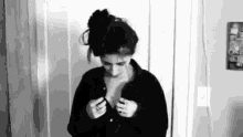 a black and white photo of a woman in a black shirt taking off her shirt .