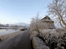 a house with a thatched roof sits on the side of a road