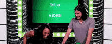 a man and a woman are standing next to each other in front of a green screen .